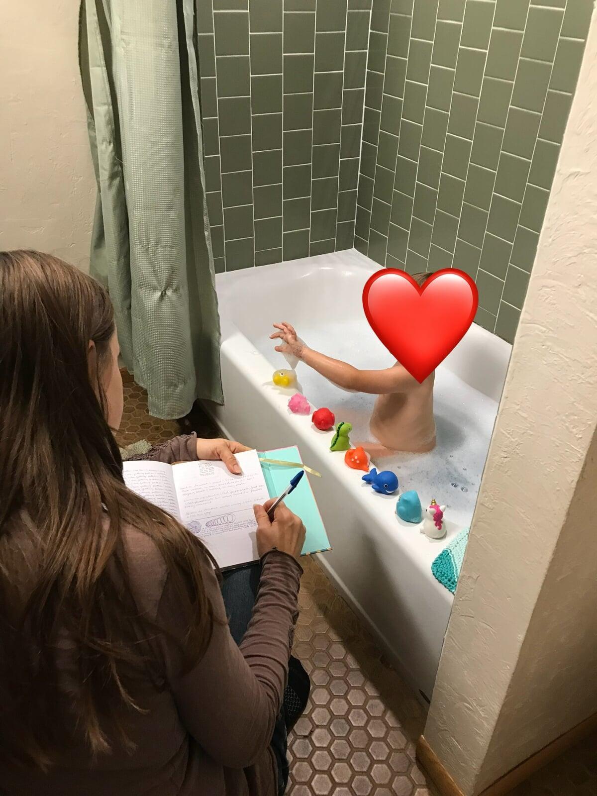 Me sitting on a stool to journal while my son is busy having fun counting his bath toys at bath time. Sometimes our best moments for self-care are when we're living life side by side our kids.
